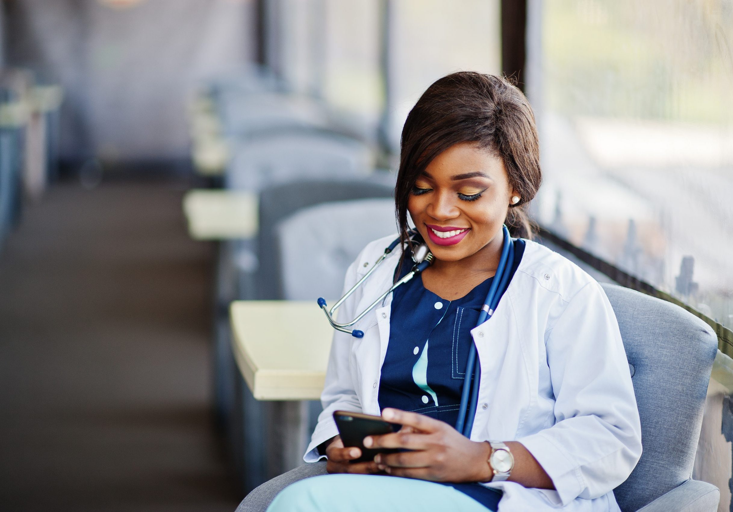 African american doctor female with stethoscope looked at phone and sitting on clinic.